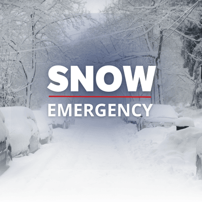 Snow covered vehicles parked on the street. 